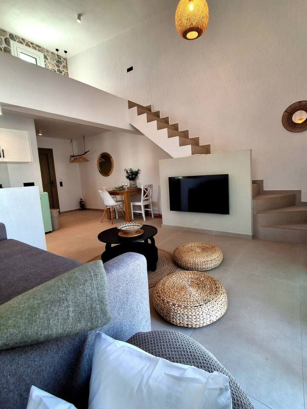 Een moderne woonkamer met een flatscreen televisie, een trap en een eethoek.