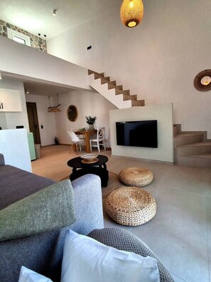 Uma sala de estar moderna com televisão de tela plana, uma escada e um espaço de jantar.