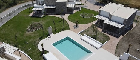 Un moderno complejo arquitectónico con una piscina central, rodeado de zonas ajardinadas y edificios adicionales.