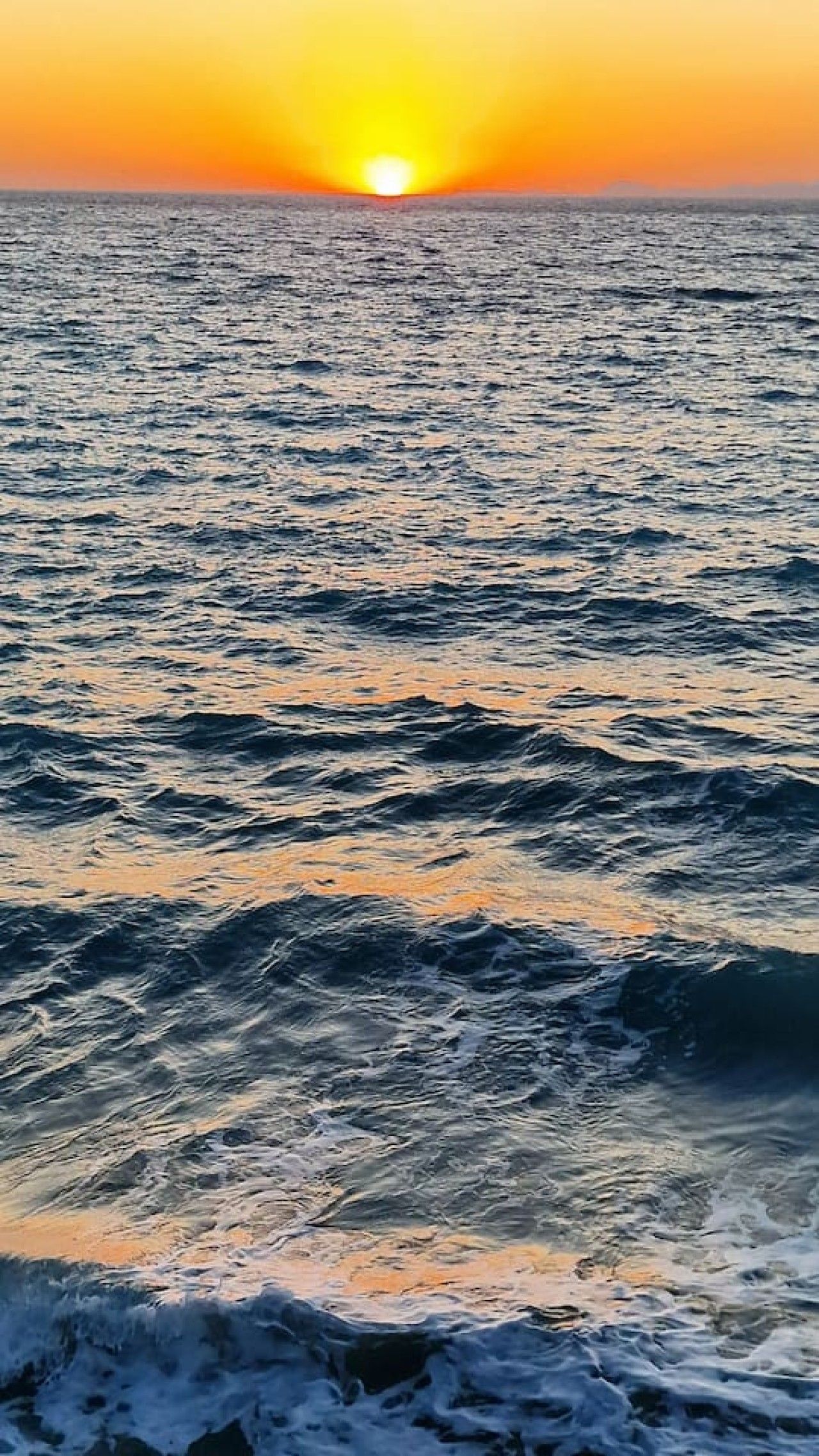 Ein Sonnenuntergang über einem Gewässer mit Wellen.