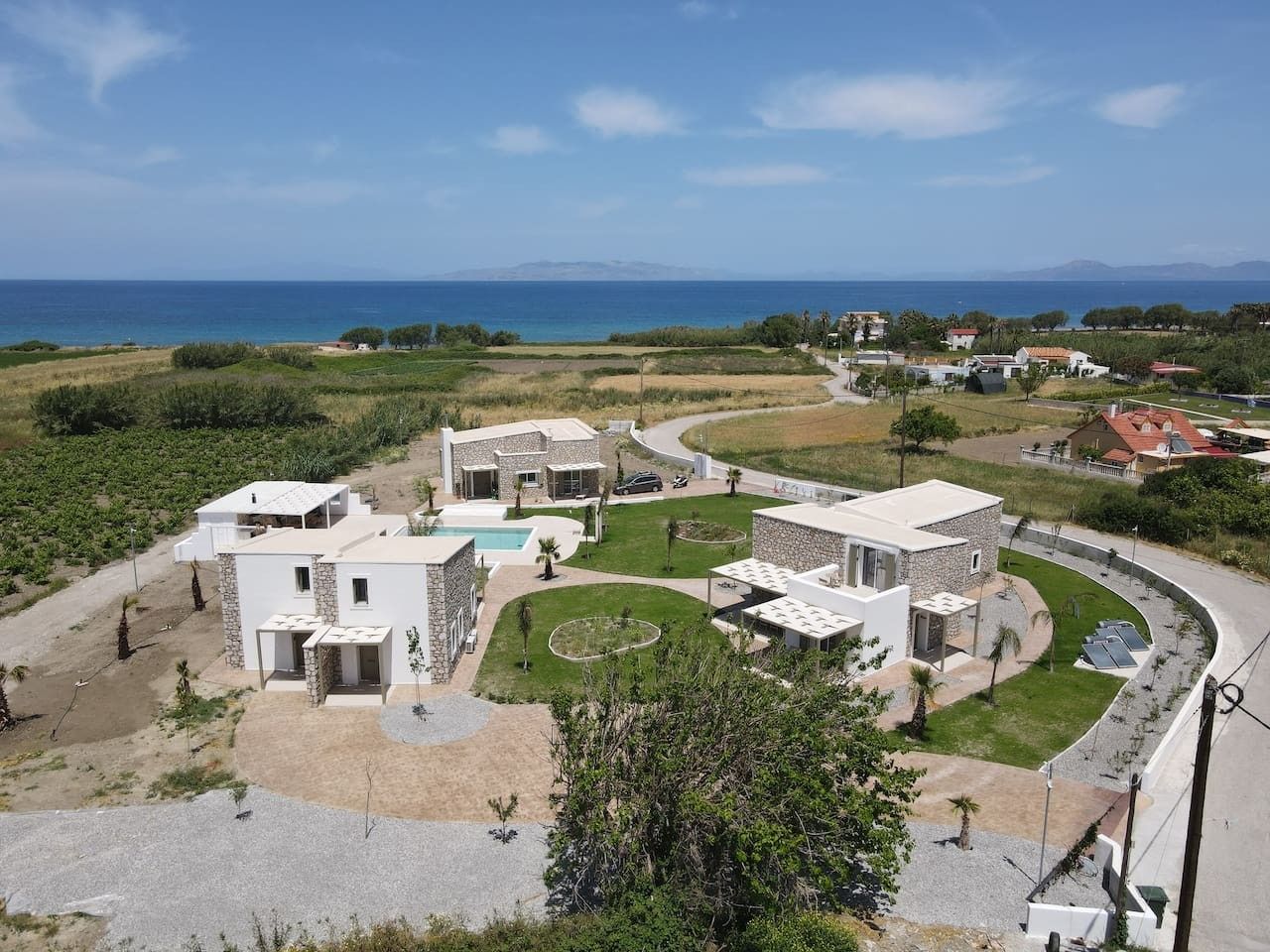 A residential area with modern houses, a swimming pool, and a curved road.