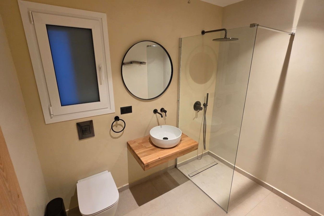 A modern bathroom with a toilet, a sink, a mirror, and a glass shower enclosure.