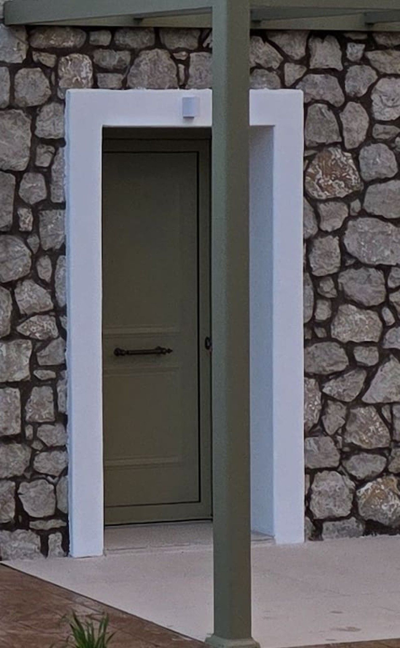 A stone wall with a door and a white frame.
