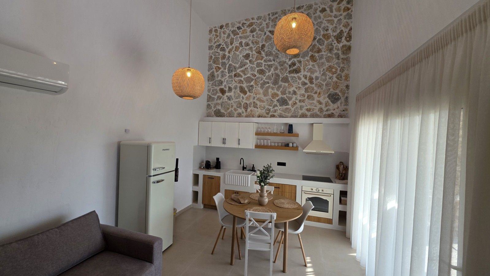 Un espace de vie compact comprenant un coin cuisine, un coin repas et un canapé.
