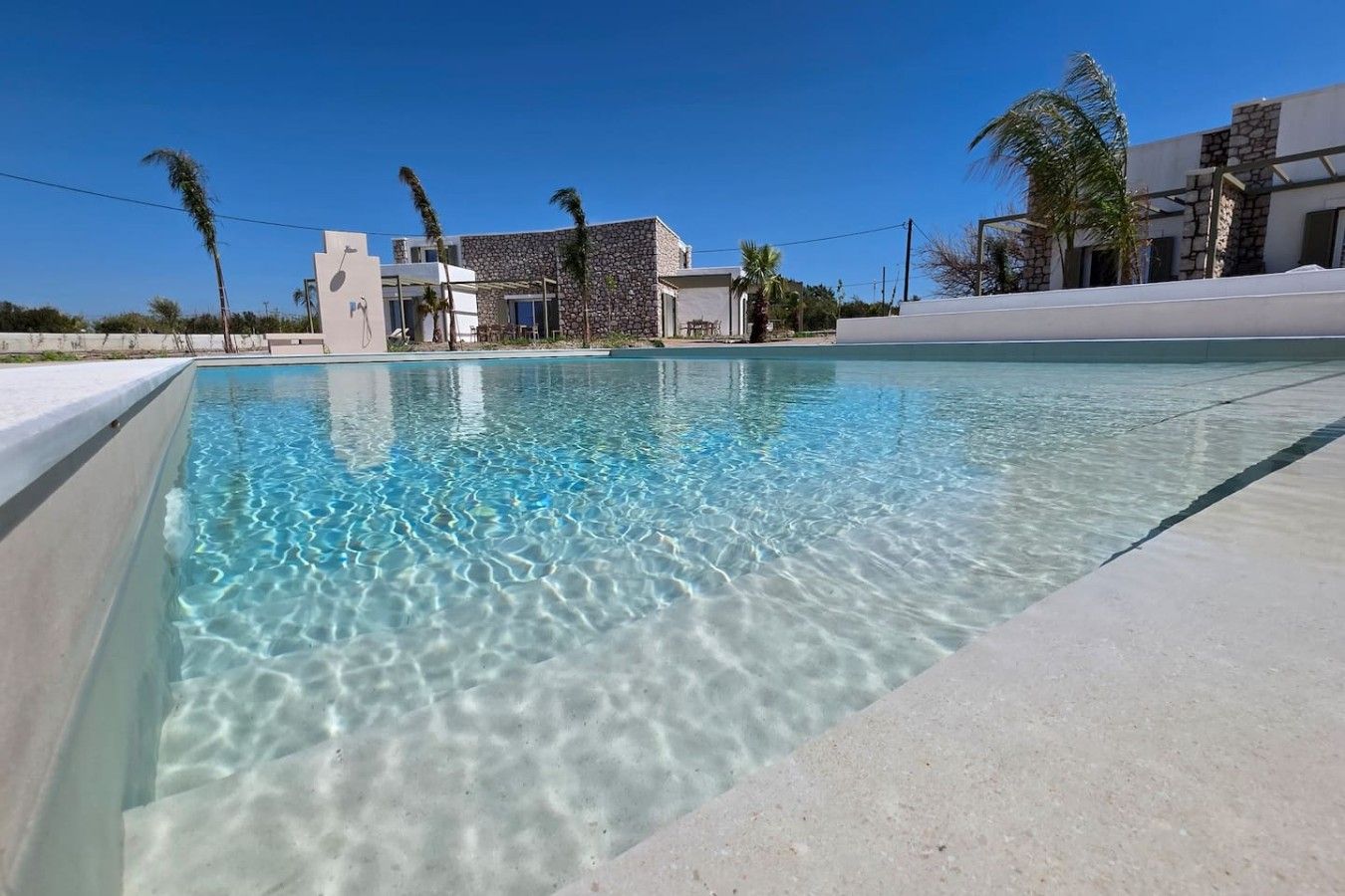 Ein klares Schwimmbecken mit einem Gebäude im Hintergrund, dessen Fassade aus Stein ist.