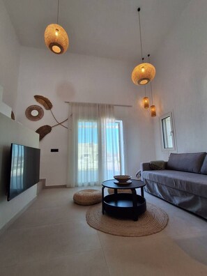 Een moderne woonkamer met een flatscreen televisie, een bank, een salontafel en twee hanglampen.