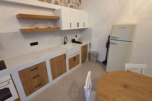 A compact kitchen with white cabinets, a wooden countertop, a built-in oven, and a refrigerator. - Fanes Breeze Lodges - Lodge Olive (Fanes)