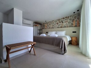 A bedroom with a bed, a bench, a stone wall, and a hanging light fixture. - Fanes Breeze Lodges - Lodge Olive (Fanes)