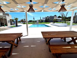 An outdoor patio area with a pool, wooden tables, and a covered seating area. - Fanes Breeze Lodges - Lodge Olive (Fanes)