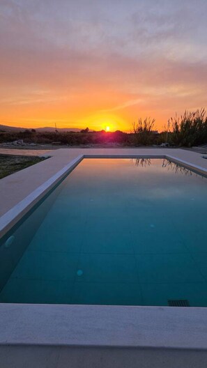 Une piscine rectangulaire à l’eau d’un bleu limpide, entourée d’une terrasse dallée.