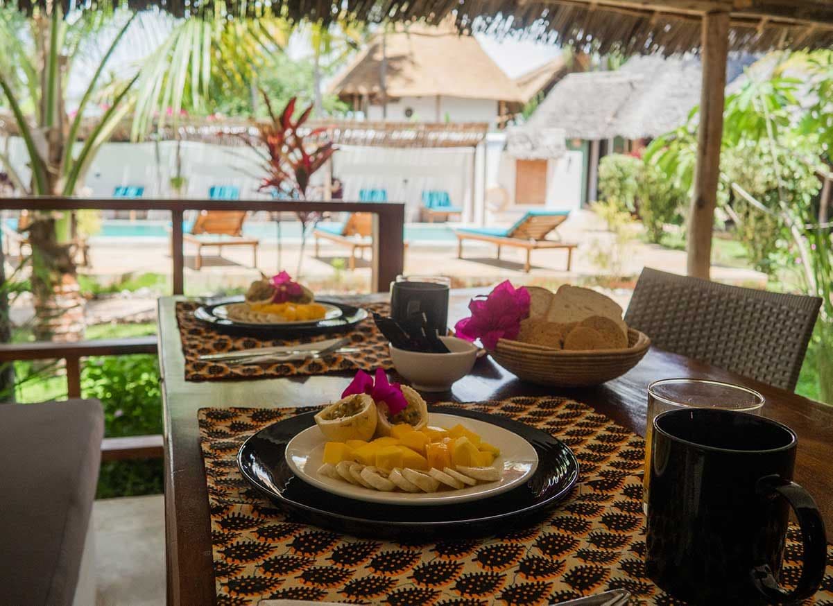 An outdoor dining area with a table set for two, featuring a plate of food and a black mug.