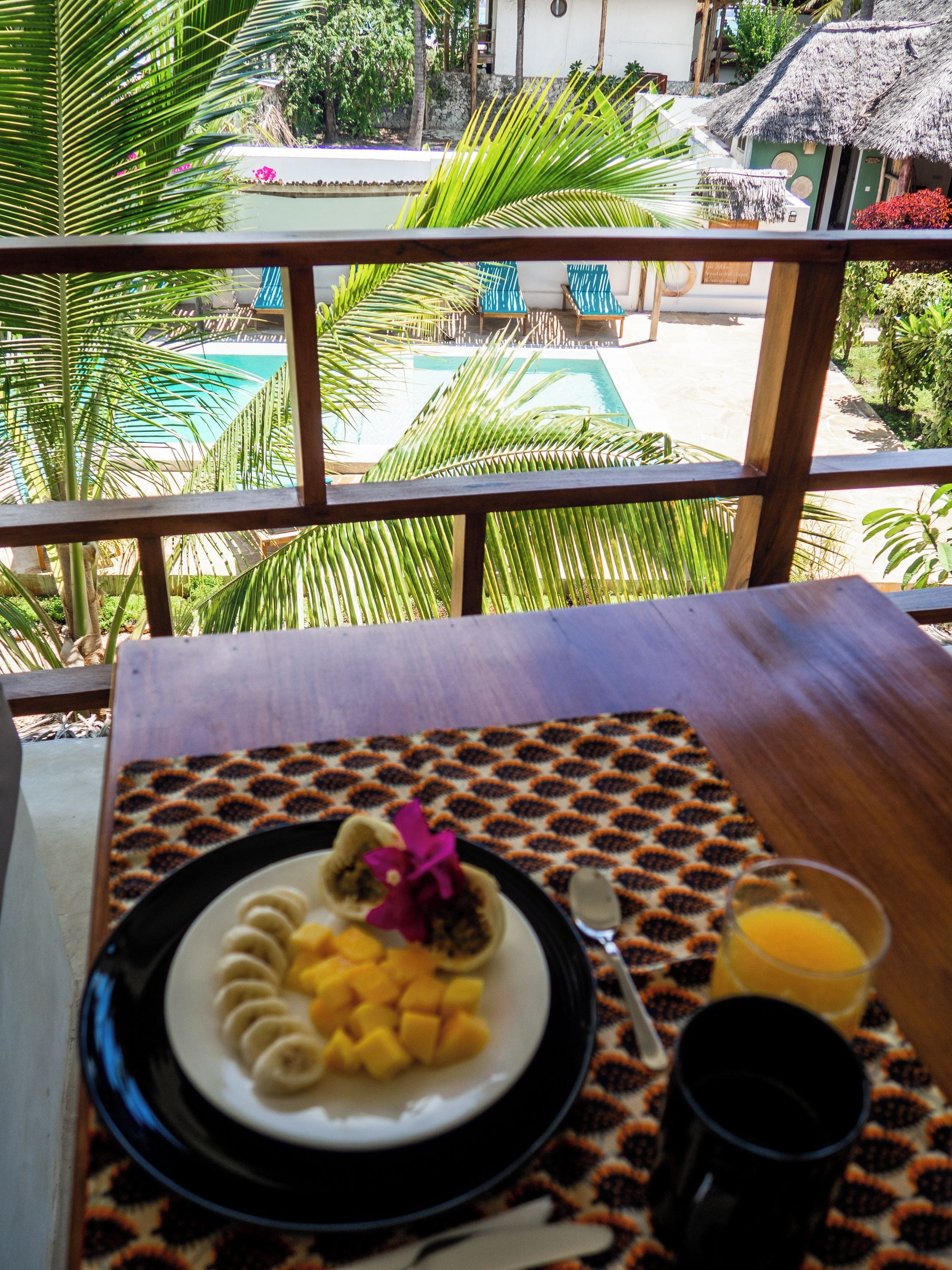 A dining table with a plate of food, a spoon, and a glass of orange juice.
