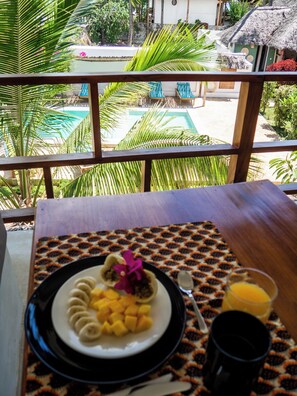 Una mesa de comedor con un plato de comida, una cuchara y un vaso de jugo de naranja.