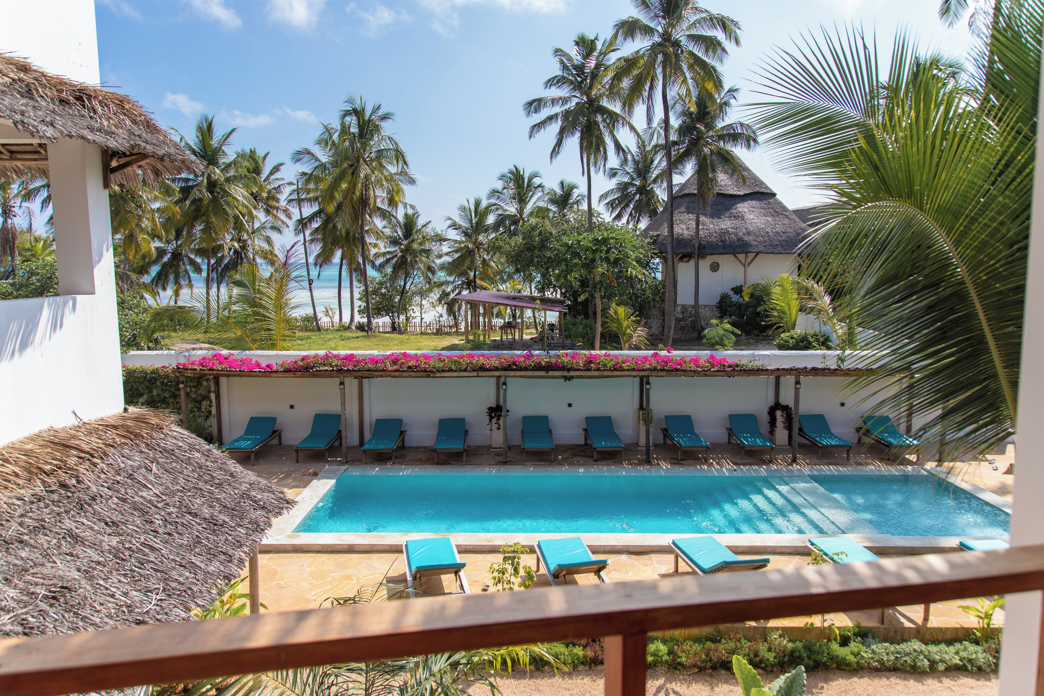A pool area with lounge chairs and a thatched-roof structure.