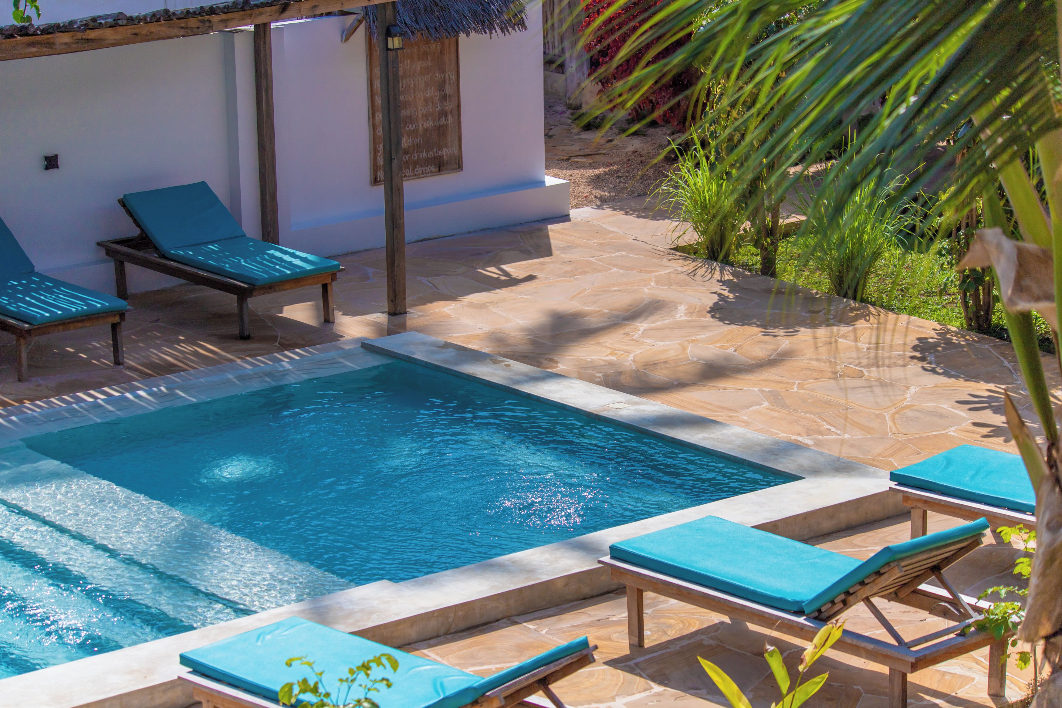 Una piscina con sillas de descanso y un patio de piedra.