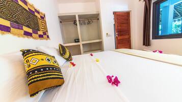 A hotel room with a bed, a wardrobe, a window, and a wall with a patterned tapestry.