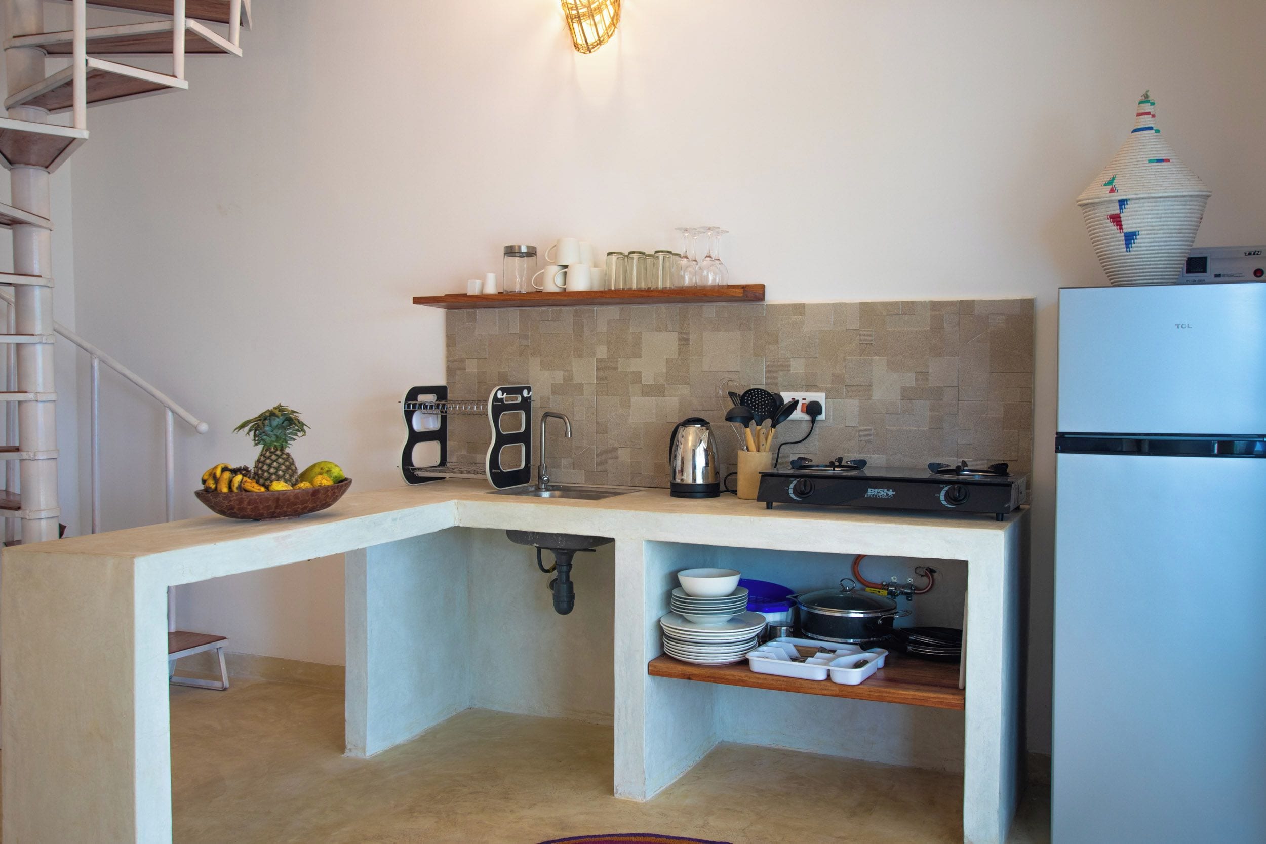 A compact kitchen with a built-in island, a coffee maker, a kettle, and a stove.