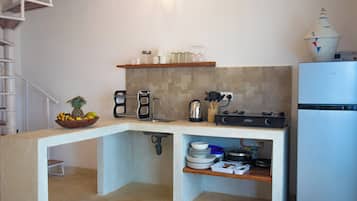 A compact kitchen with a built-in island, a coffee maker, a kettle, and a stove.