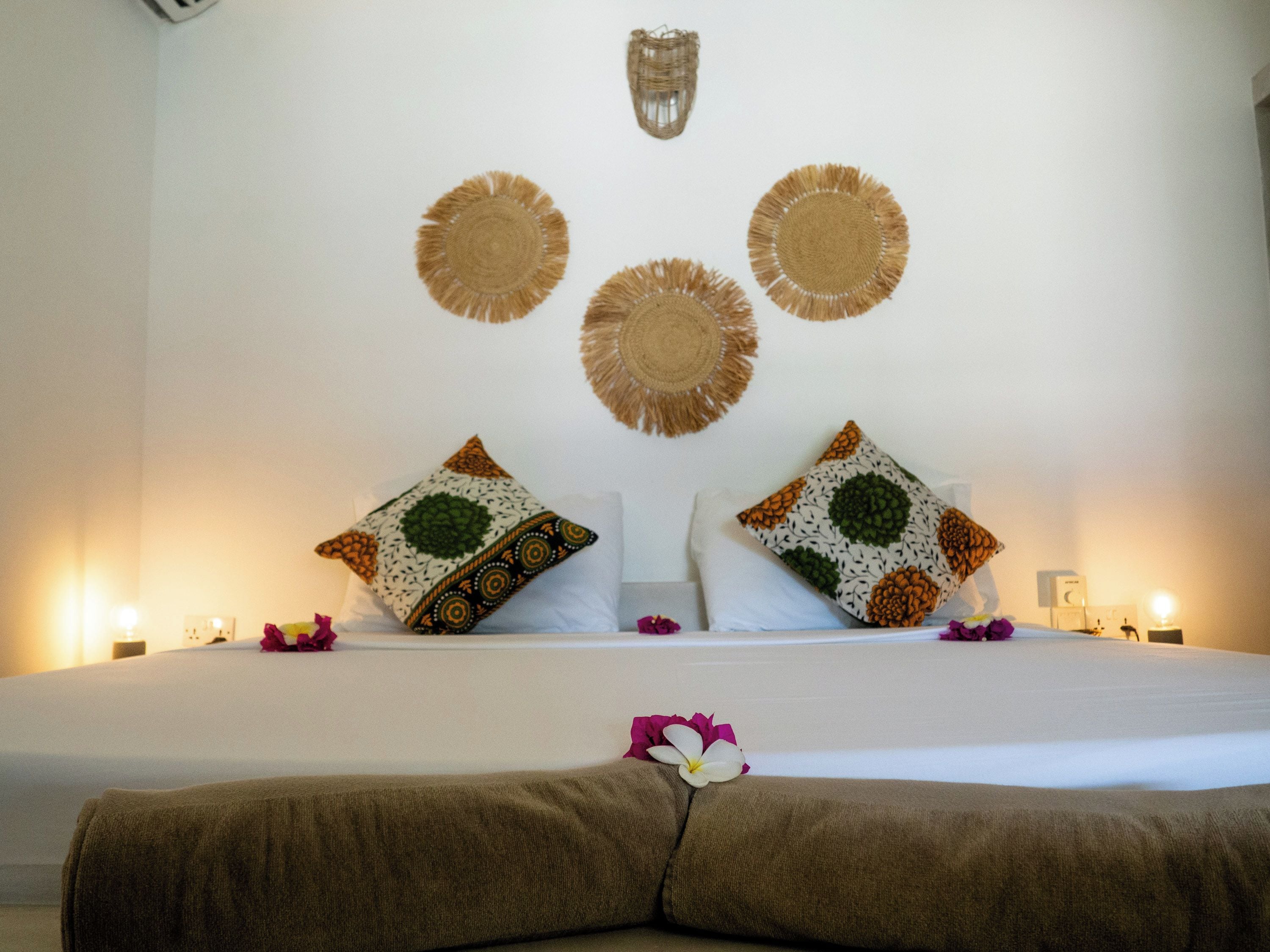 A neatly made bed with a pillow and a decorative wall hanging above it.