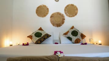 A neatly made bed with a pillow and a decorative wall hanging above it.