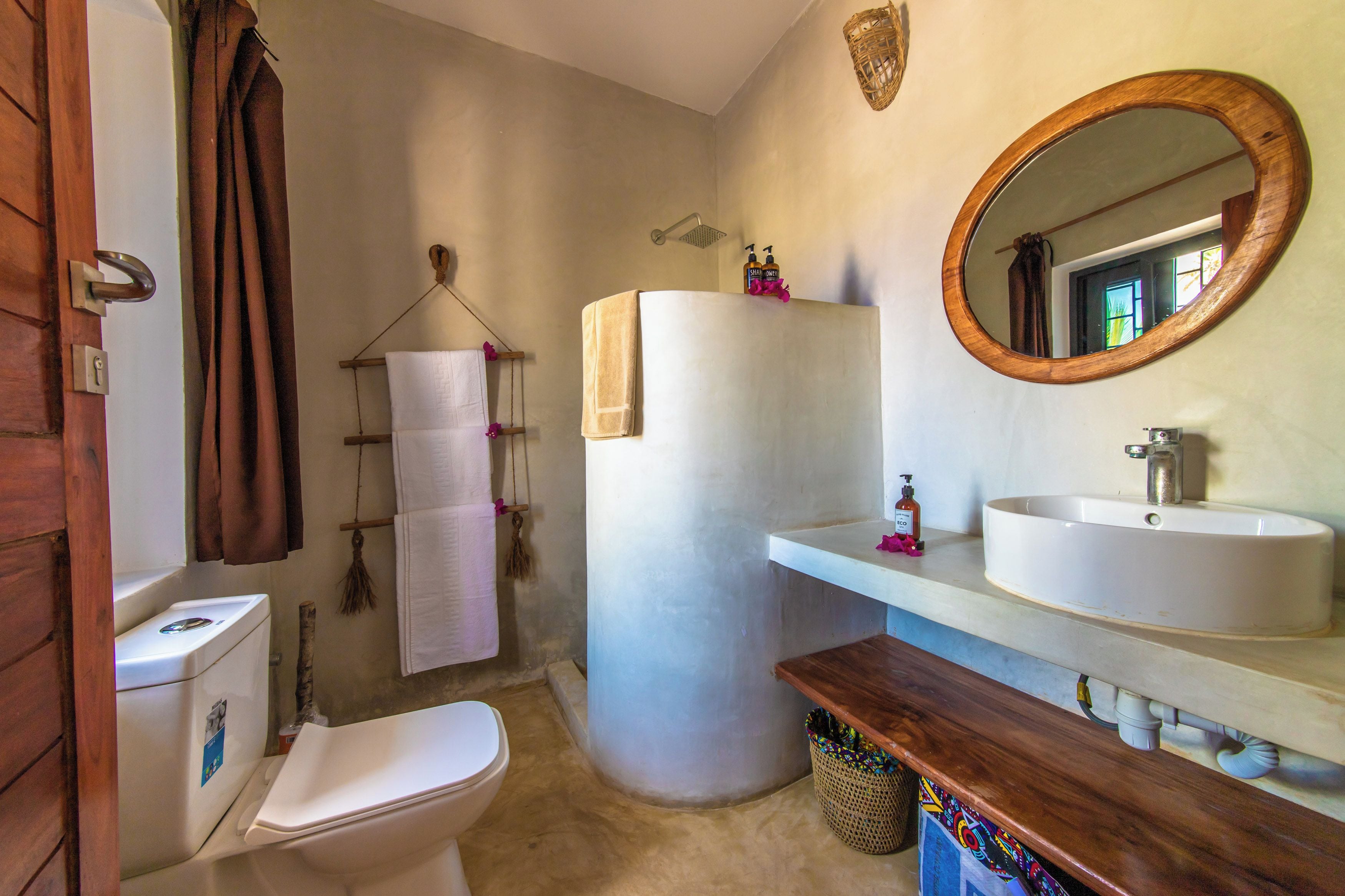 A bathroom with a toilet, sink, mirror, and towel rack.
