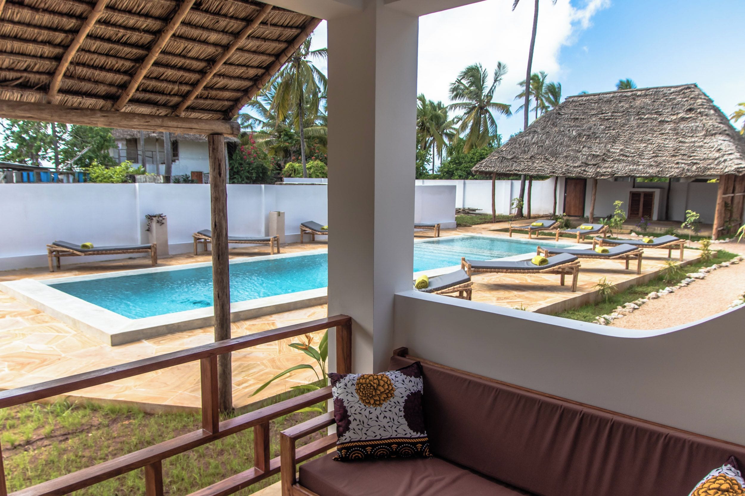 A pool area with lounge chairs and a thatched-roof structure.