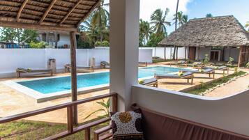 A pool area with lounge chairs and a thatched-roof structure.