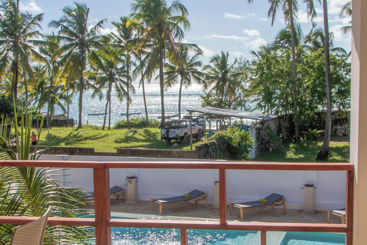 A poolside area with lounge chairs and a view of the sea.