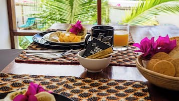 A breakfast table with plates of food, a bowl of brown sugar, and a glass of orange juice.