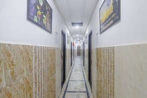 Un couloir aux murs de marbre, orné de tableaux encadrés et doté d’un sol carrelé.