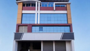 A multi-story building with a flat roof, large windows, and a set of stairs leading to the entrance. - Deluxe Hotel Ashoka Grand (Sadasivpet)