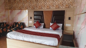 A hotel room with a large bed, a headboard with floral patterns, and a patterned wall. - Classic Hotel City (Dumka)