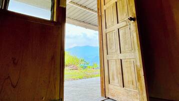 An open wooden door leading to an outdoor area with a view of mountains.