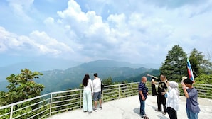 Un grupo de personas sobre una plataforma de observación con barandilla, contemplando un paisaje montañoso.