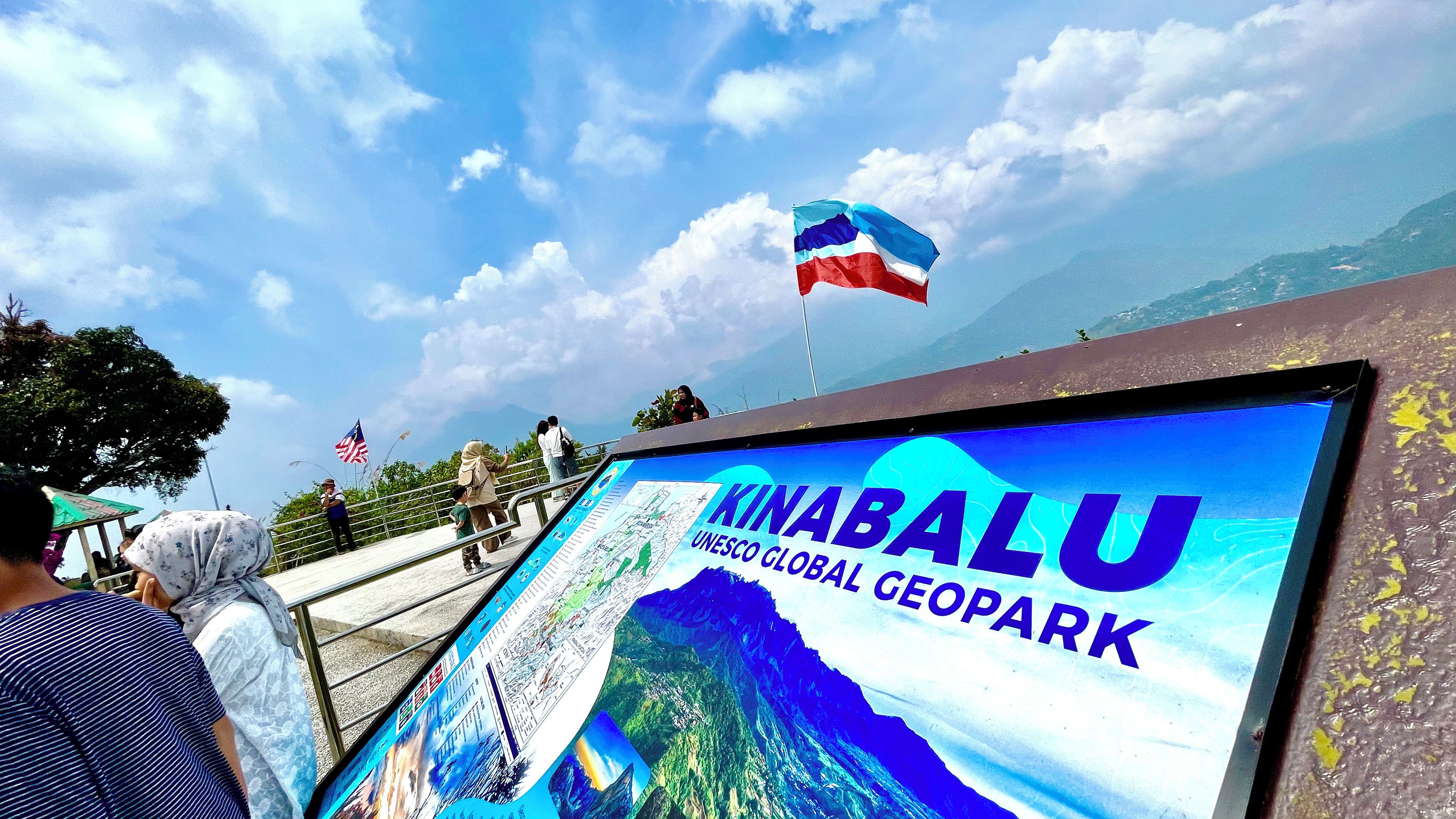 A sign for Kinabalu UNESCO Global Geopark with a map and a flag.