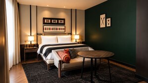 Ett hotellrum med en säng, sängbord, ett runt bord och en mörkgrön accentvägg.