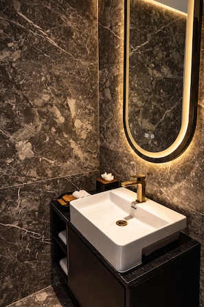A modern bathroom with a white sink, gold faucet, and a mirror with a gold frame. - Polo Hotel Kohima (Kohima)