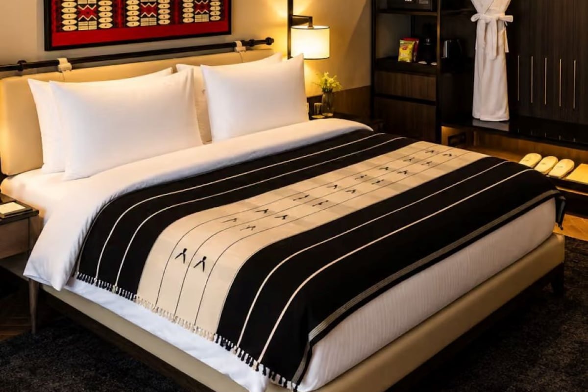 A hotel room with a bed, a nightstand, a lamp, a robe, and a wardrobe.