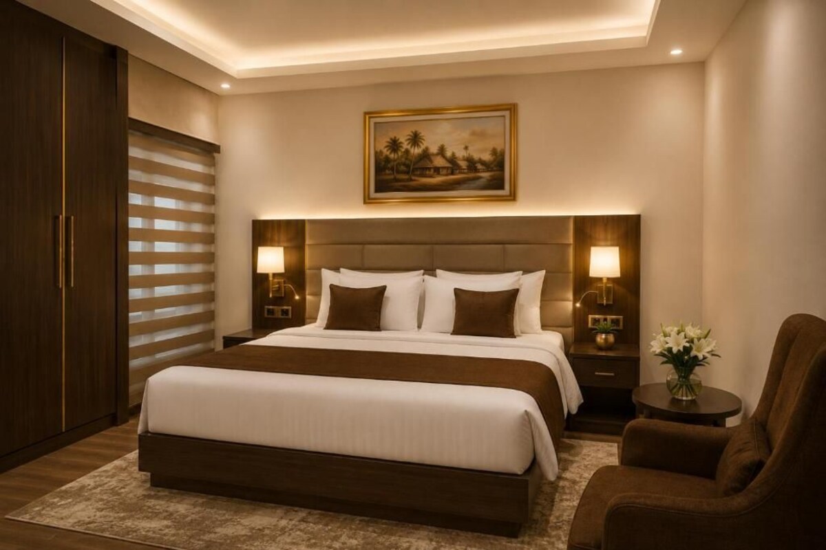 Une chambre à coucher moderne avec un grand lit, des lampes de chevet, une table de chevet, une chaise et un tableau au mur.