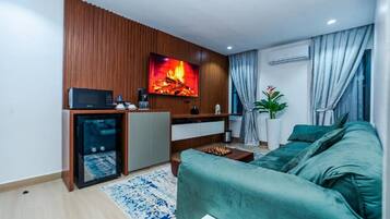 Una sala de estar moderna con un sofá verde, una pequeña mesa de centro, un televisor montado en una pared de madera y una chimenea.