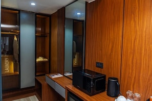 A modern bathroom with a wooden vanity, a black microwave, and a coffee maker.