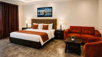 Habitación de hotel con una cama grande, un sofá, una mesita y un cuadro en la pared.