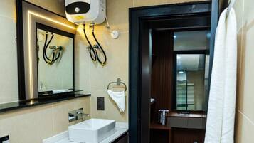 Un baño moderno con un lavamanos blanco, un espejo, un perchero para toallas y una cortina de ducha.
