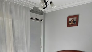 Un dormitorio con una cama, una mesita de noche, un equipo de aire acondicionado instalado en la pared y un cuadro enmarcado.