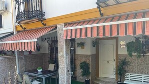 Un patio con zona de estar cubierta, una puerta y plantas en macetas.