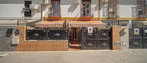 A building with a gated entrance, multiple air conditioning units, and a tiled roof.