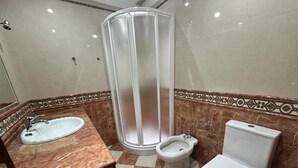 Un baño con lavamanos, bidé, inodoro y cabina de ducha.