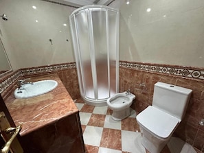Un baño con lavamanos, bidé, inodoro y cabina de ducha.
