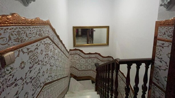 Una escalera con diseños ornamentales en las paredes y un espejo.