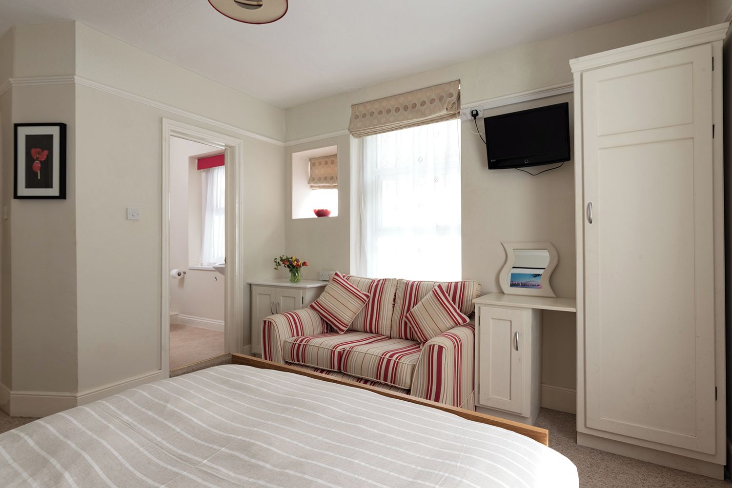 A bedroom with a bed, a sofa, a television, and a wardrobe.